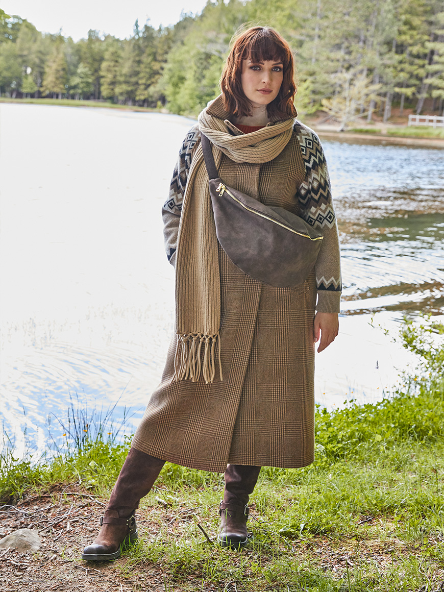 Modella indossa cappotto con decorazioni e maxi borsa marrone.